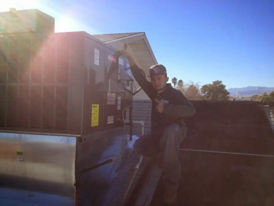 HVAC technician performing Boiler Repair on a rooftop unit in Kenai